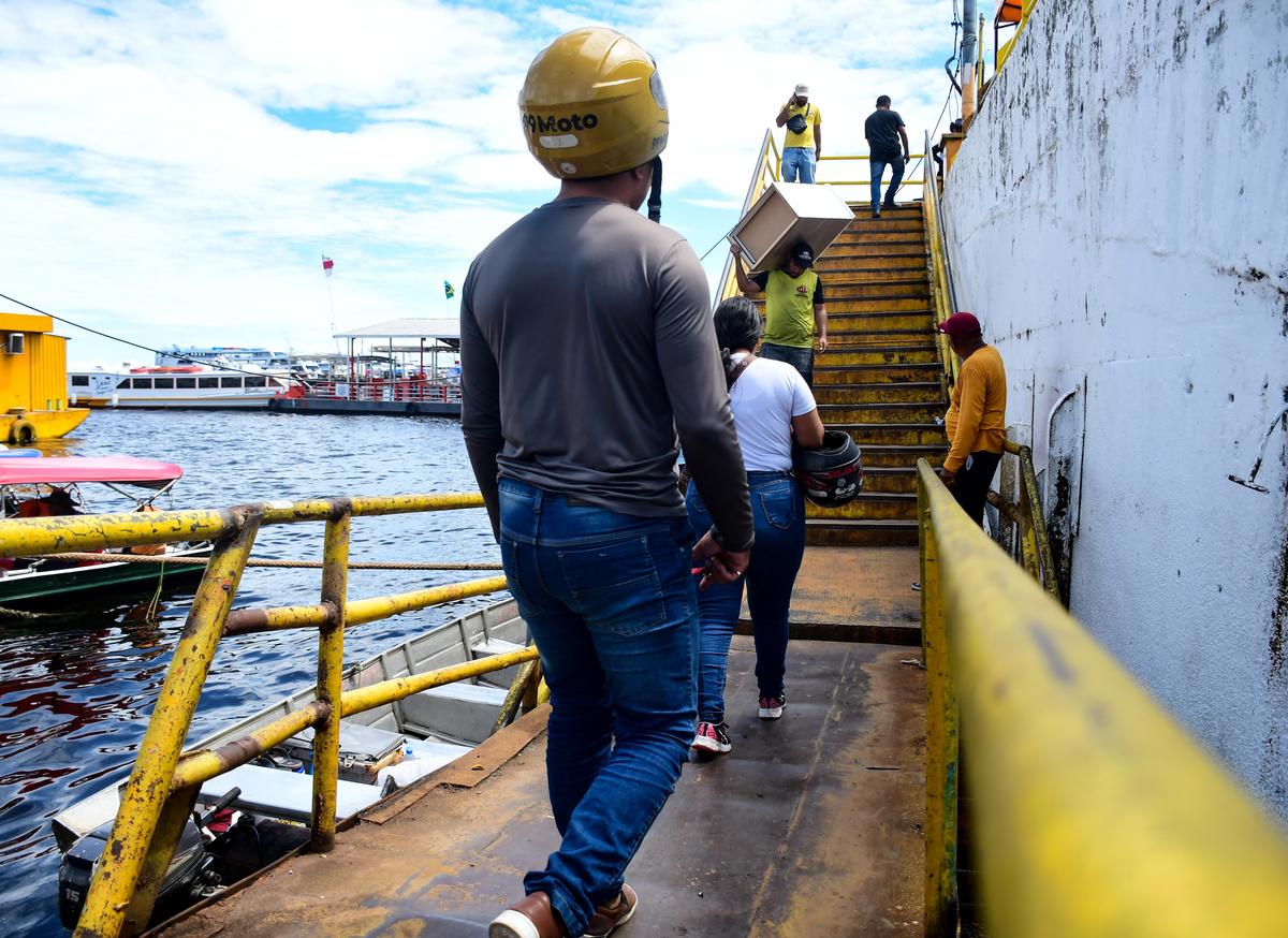 Carregadores em situação de vulnerabilidade transportam caixas pesadas sem equipamentos de proteção individual