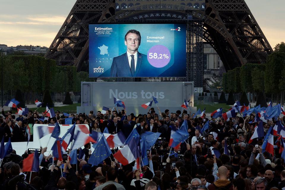 Apoiadores do presidente francês Emmanuel Macron, candidato à sua reeleição, reagem após o anúncio dos resultados no segundo turno da eleição presidencial francesa de 2022, perto da Torre Eiffel