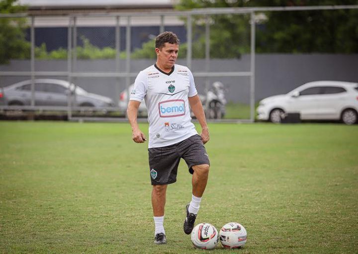 Técnico Evaristo Piza usando camisa do Manaus FC e chutando uma bola no campo de treinamento