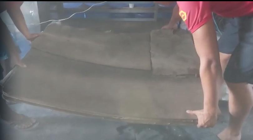 Homens retirando tapumes de embarcação, onde havia drogas escondidas