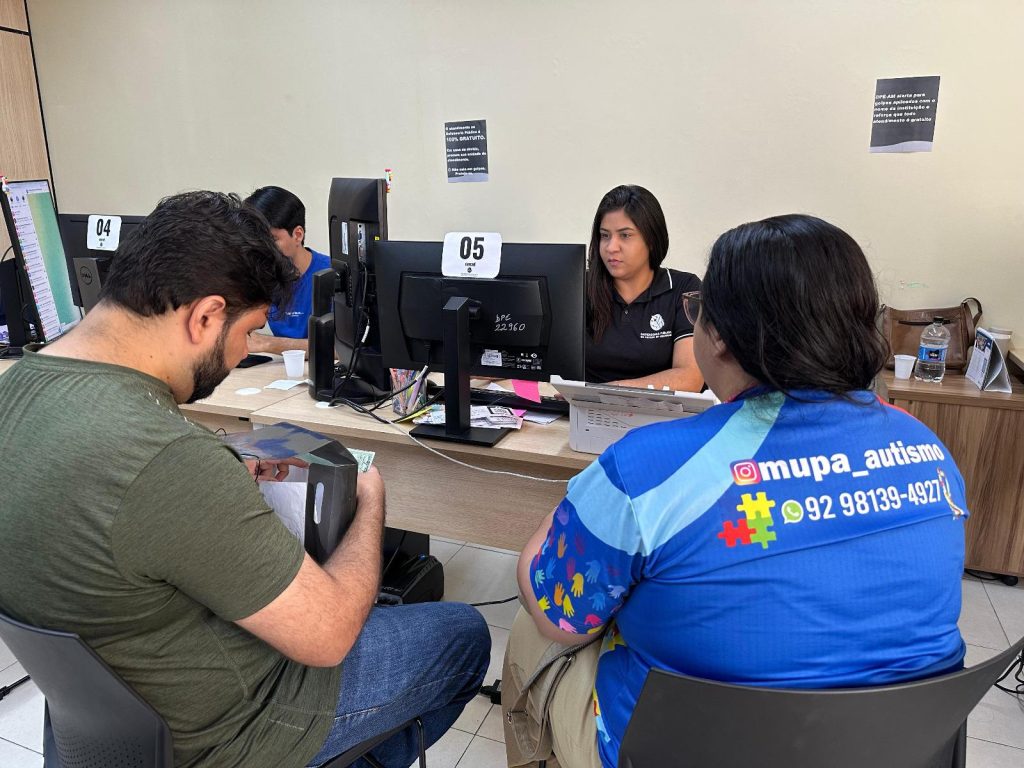 Servidores da Defensoria atendem usuários sentados em frente a computadores em ambiente de atendimento