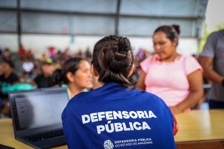 Mulher com colete azul da defensoria, atendendo a população